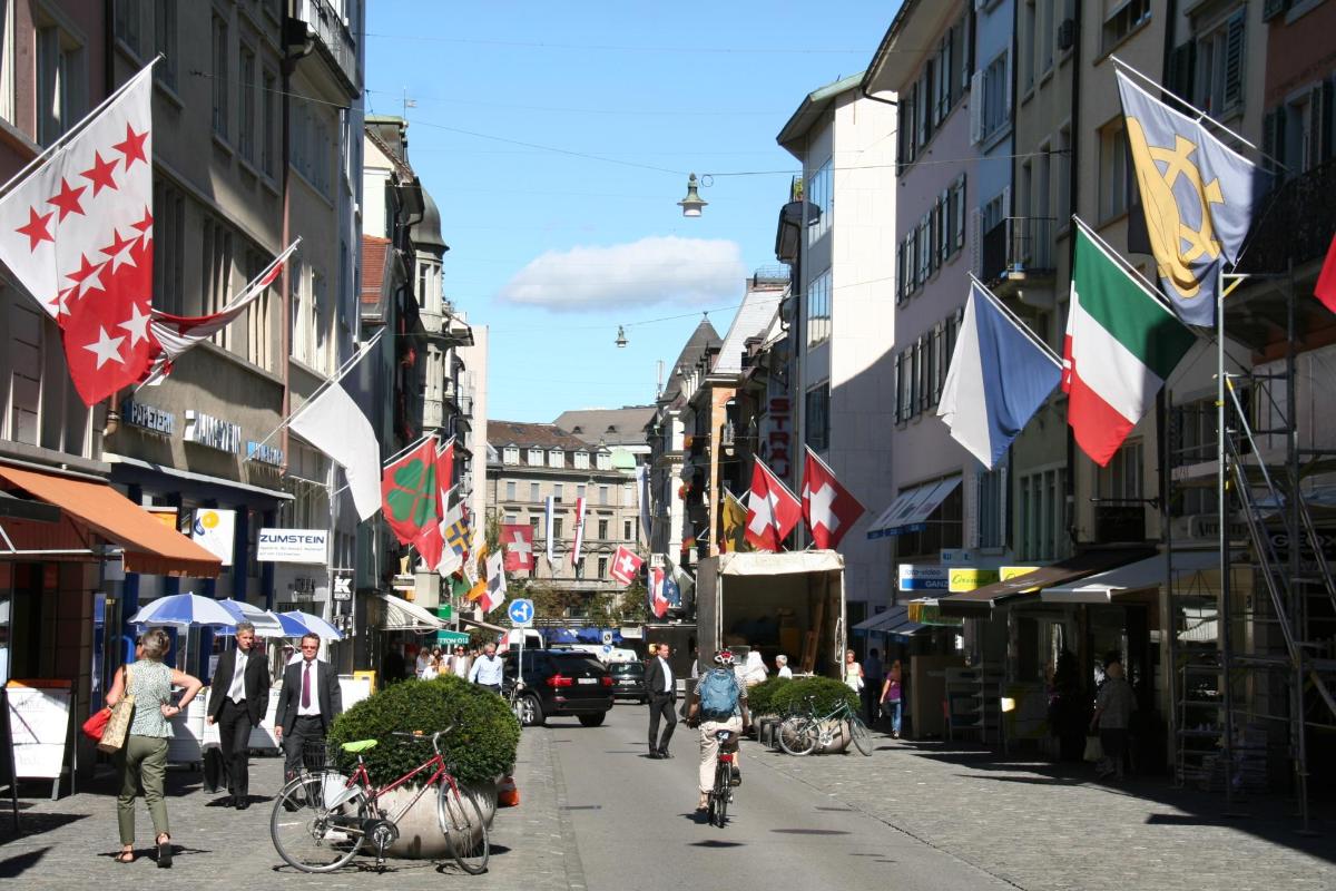 a city street with flags and people on a bike