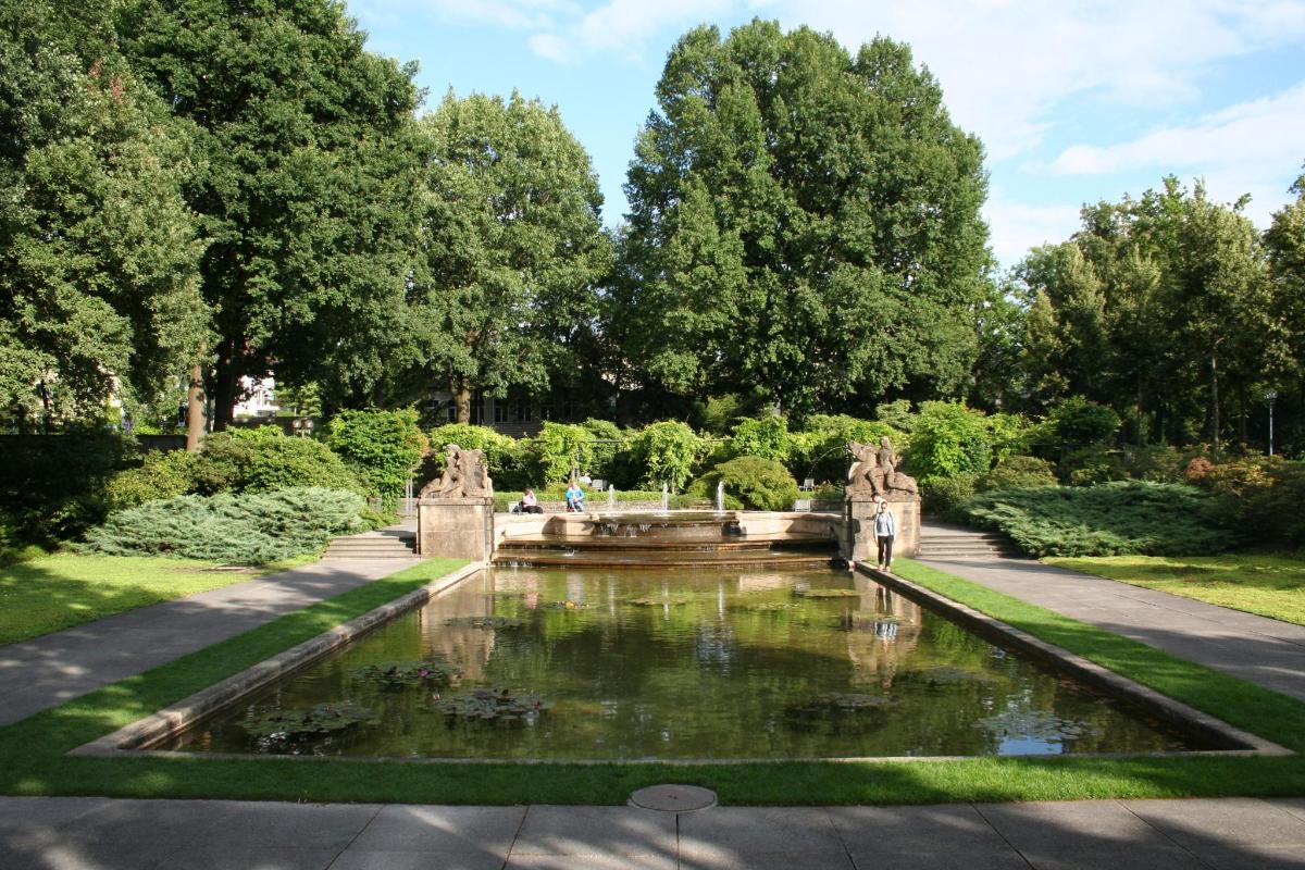 uma fonte em um jardim com árvores ao fundo