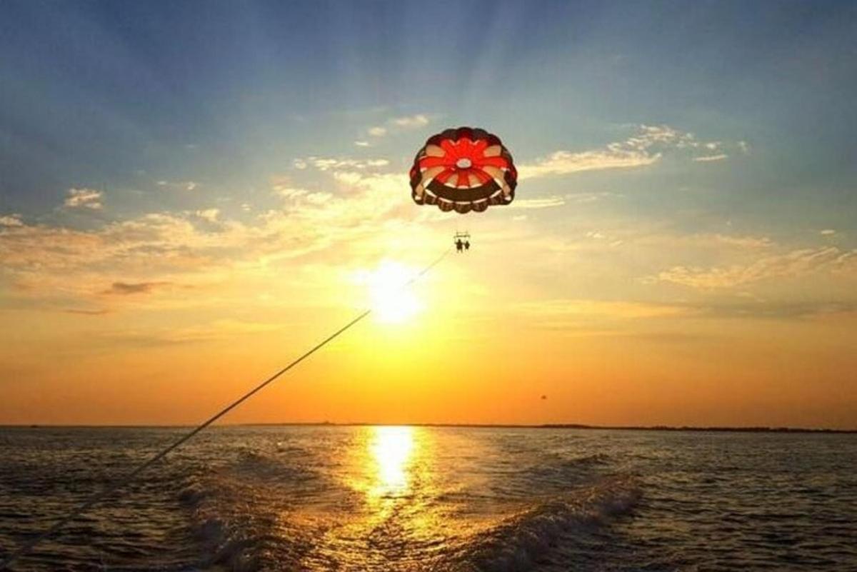 henkilö lennättää leijaa meren yllä auringonlaskun aikaan