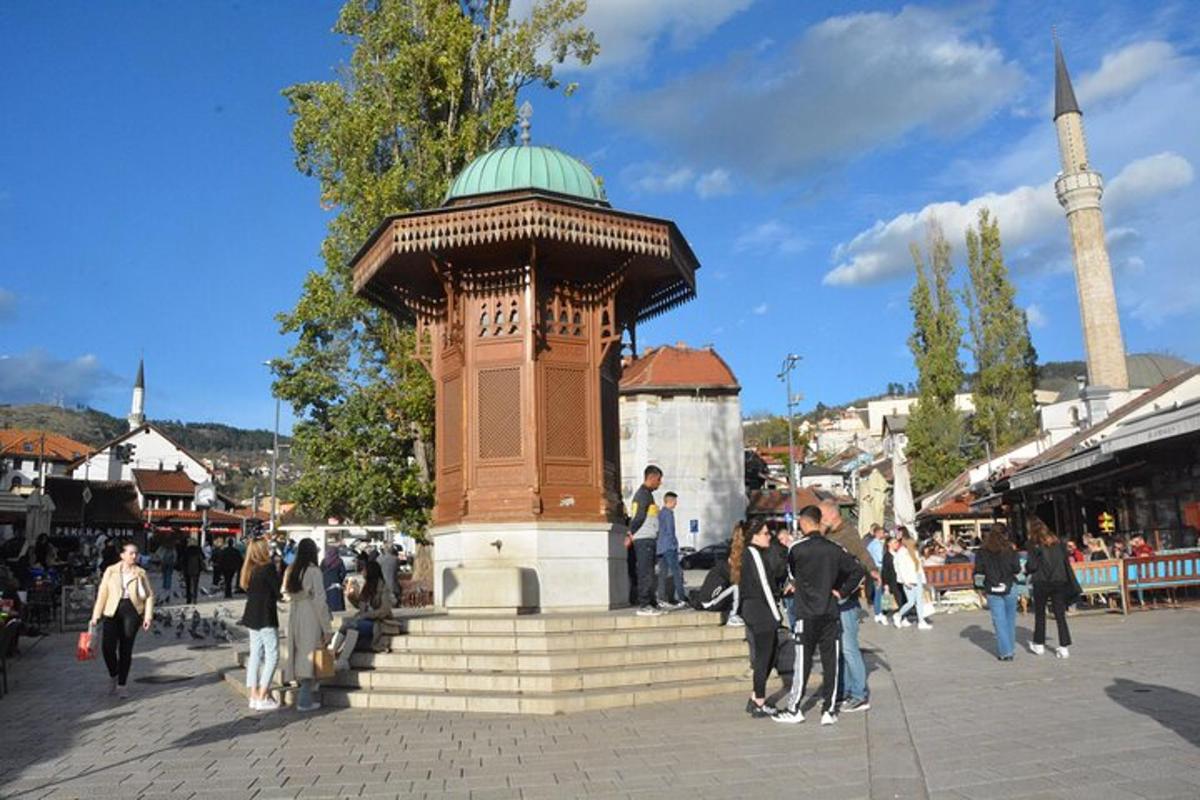 um grupo de pessoas caminhando ao redor de uma torre em uma rua