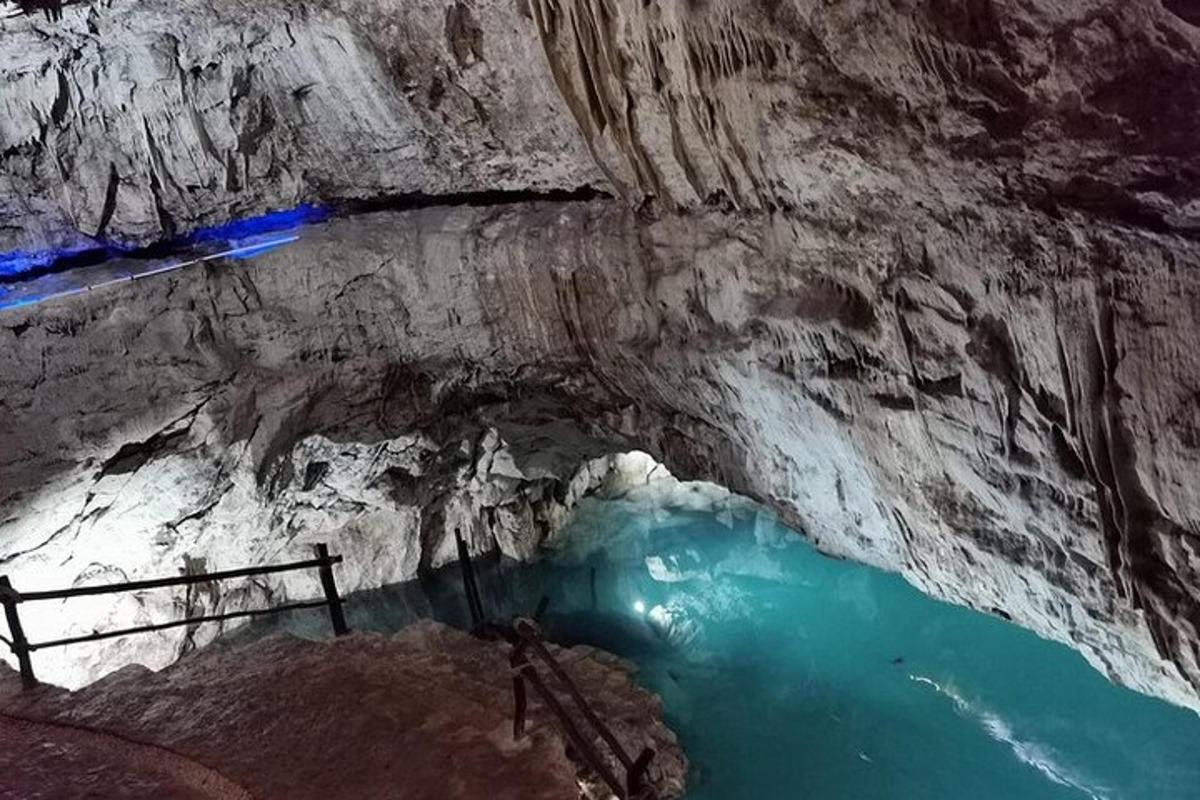 Una cueva con un estanque de agua azul en su interior.