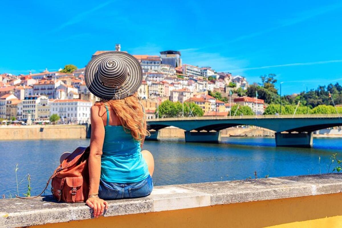 a woman sitting on a ledge looking at a river