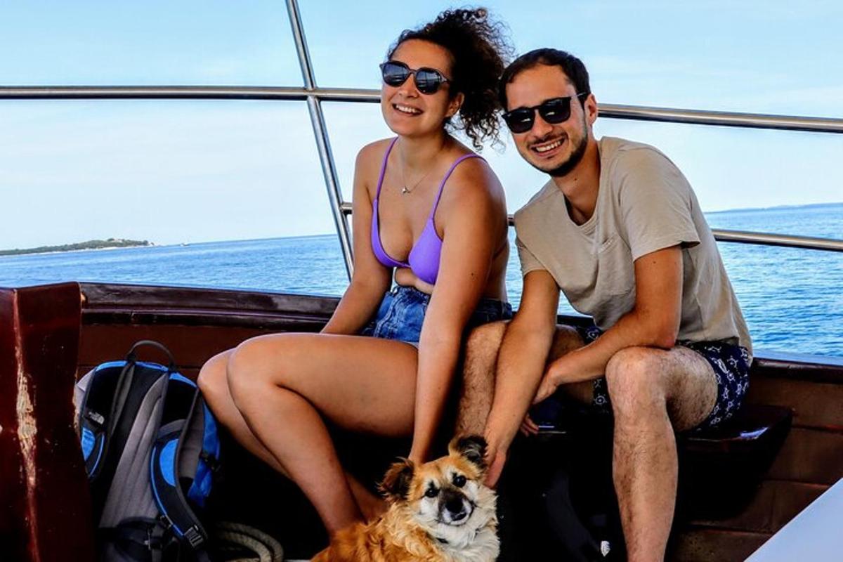 moški in ženska sedita na čolnu s psom