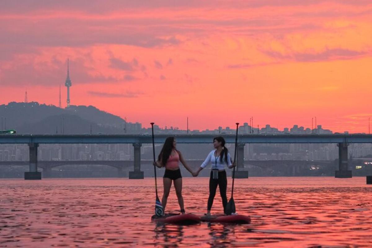 due donne in piedi su tavole da paddle in acqua al tramonto