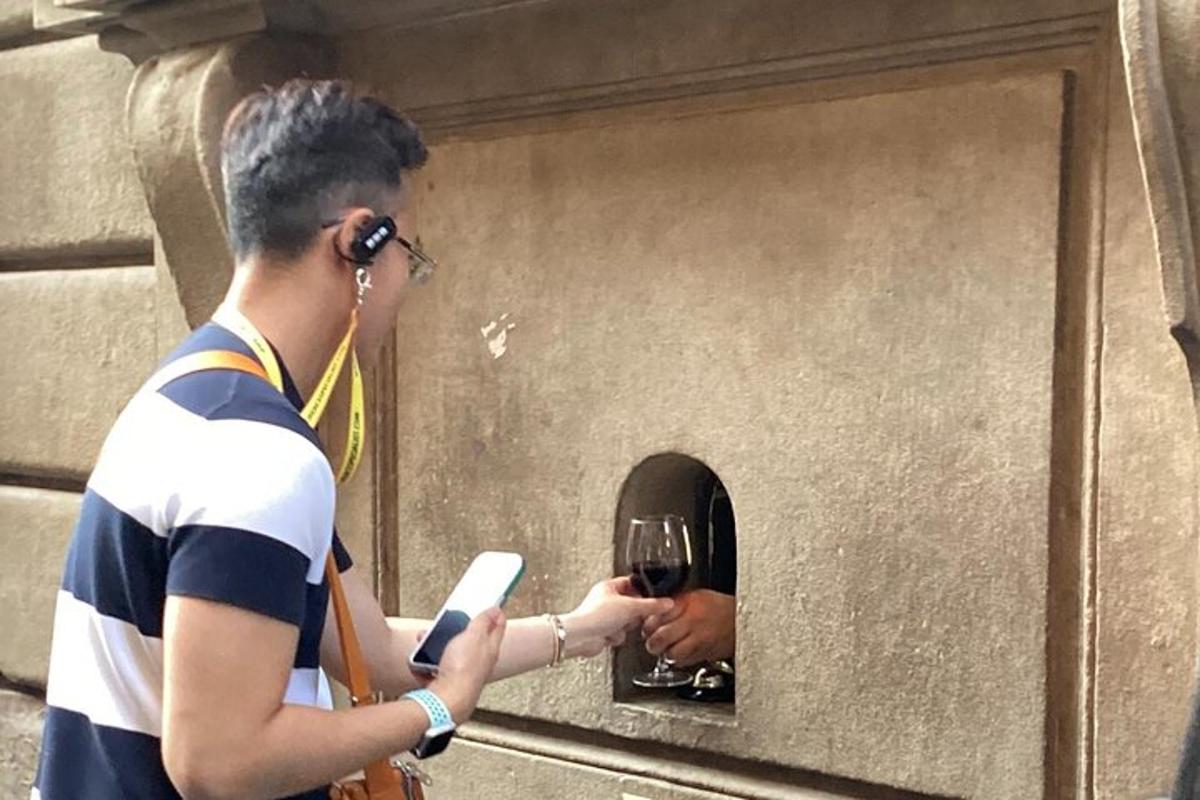 un uomo che tiene in mano un cellulare e un bicchiere di vino