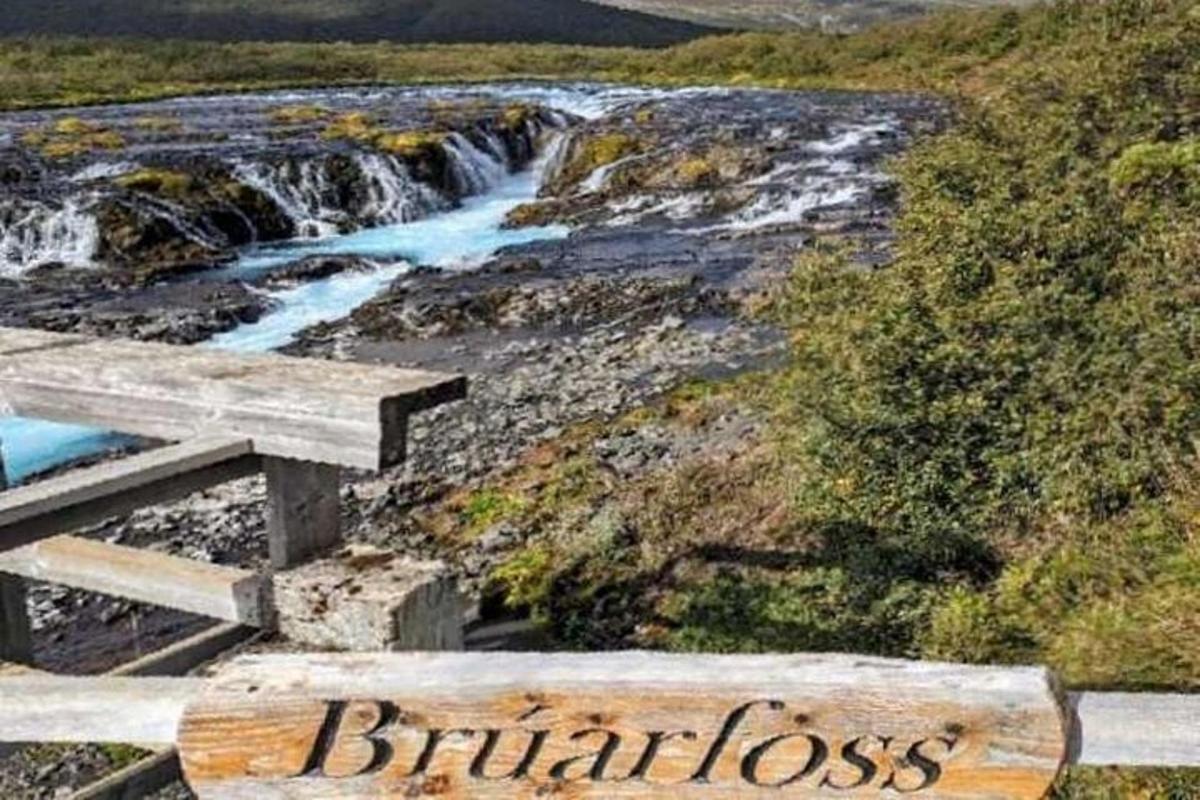 una panchina di legno accanto a un fiume con una cascata