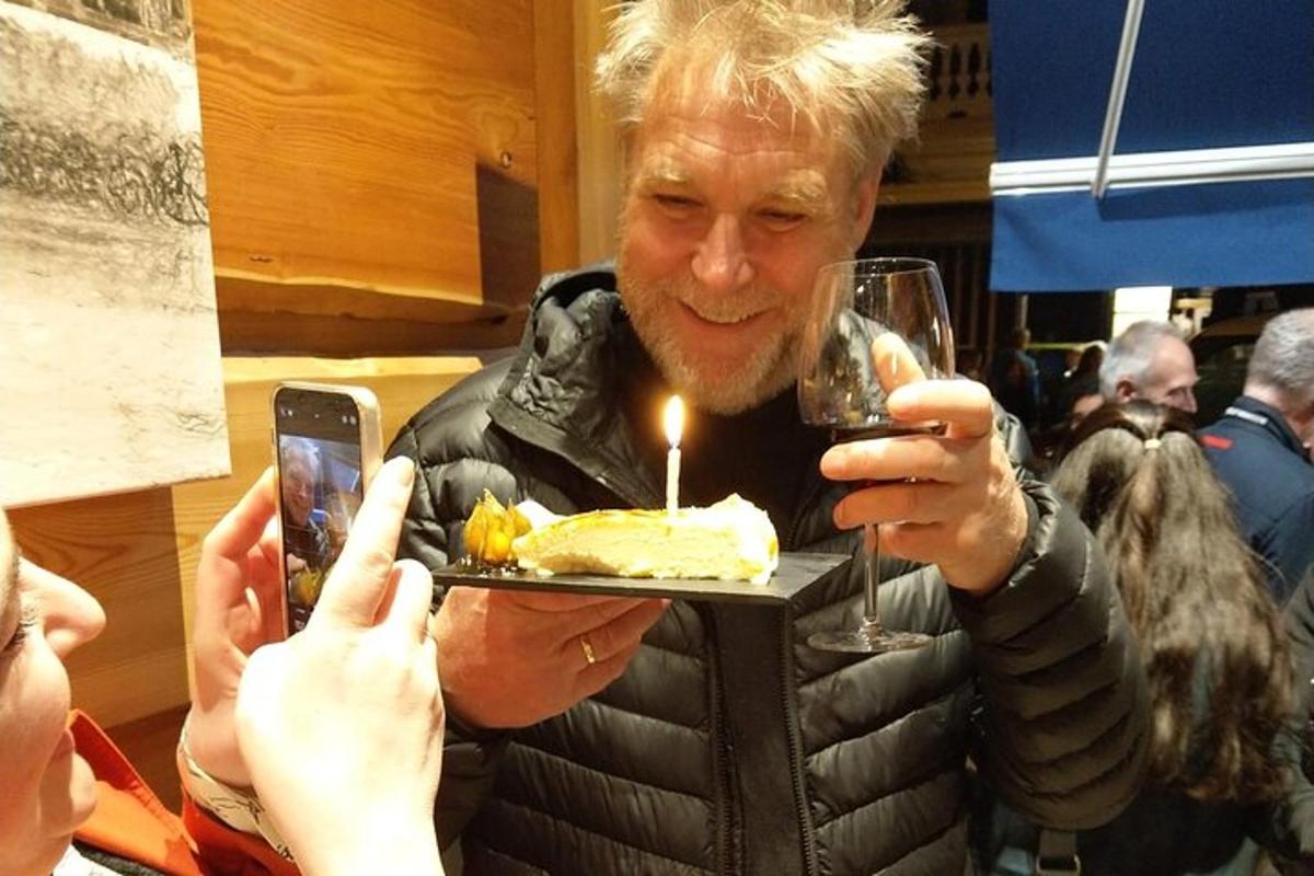Un hombre sosteniendo un plato con un pastel con una vela.