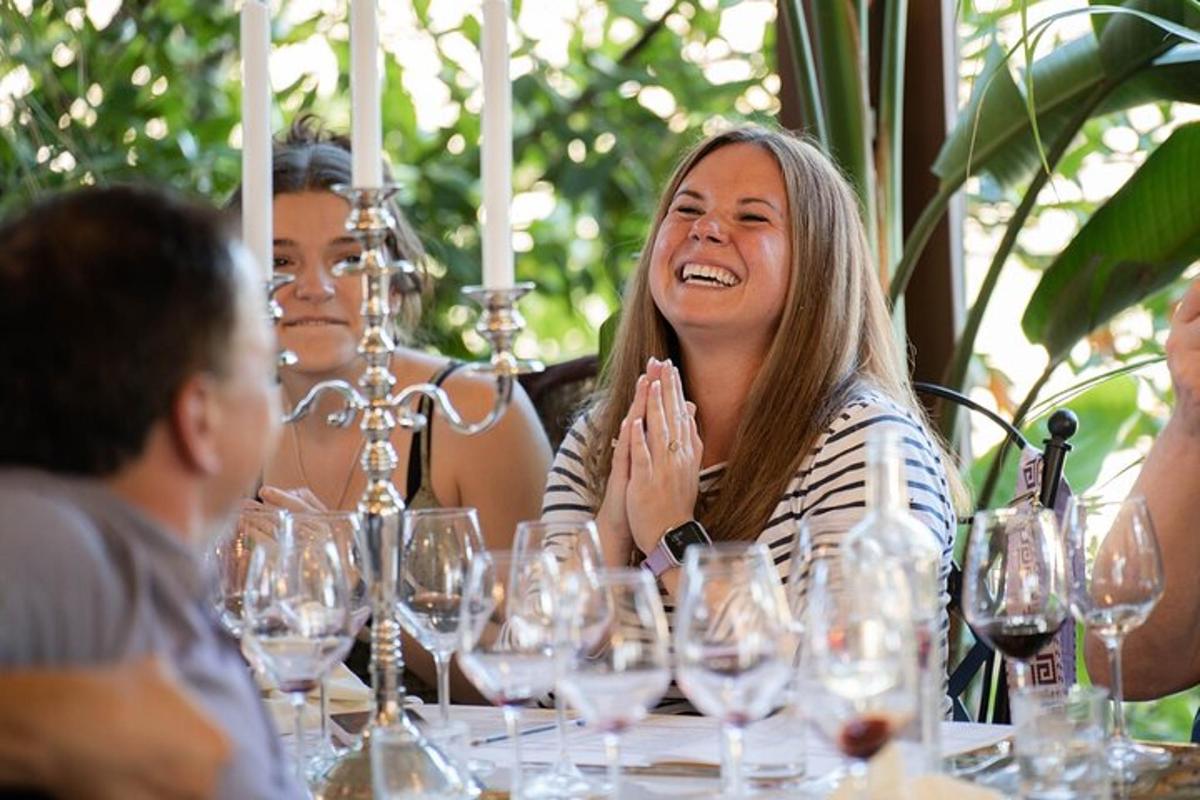 două femei așezate la o masă cu pahare de vin