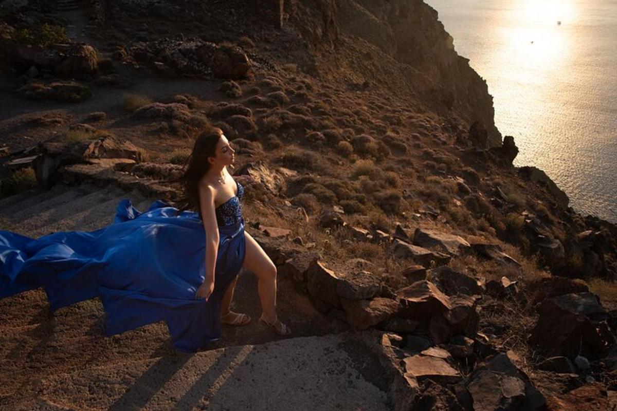 a woman in a blue dress sitting on a cliff