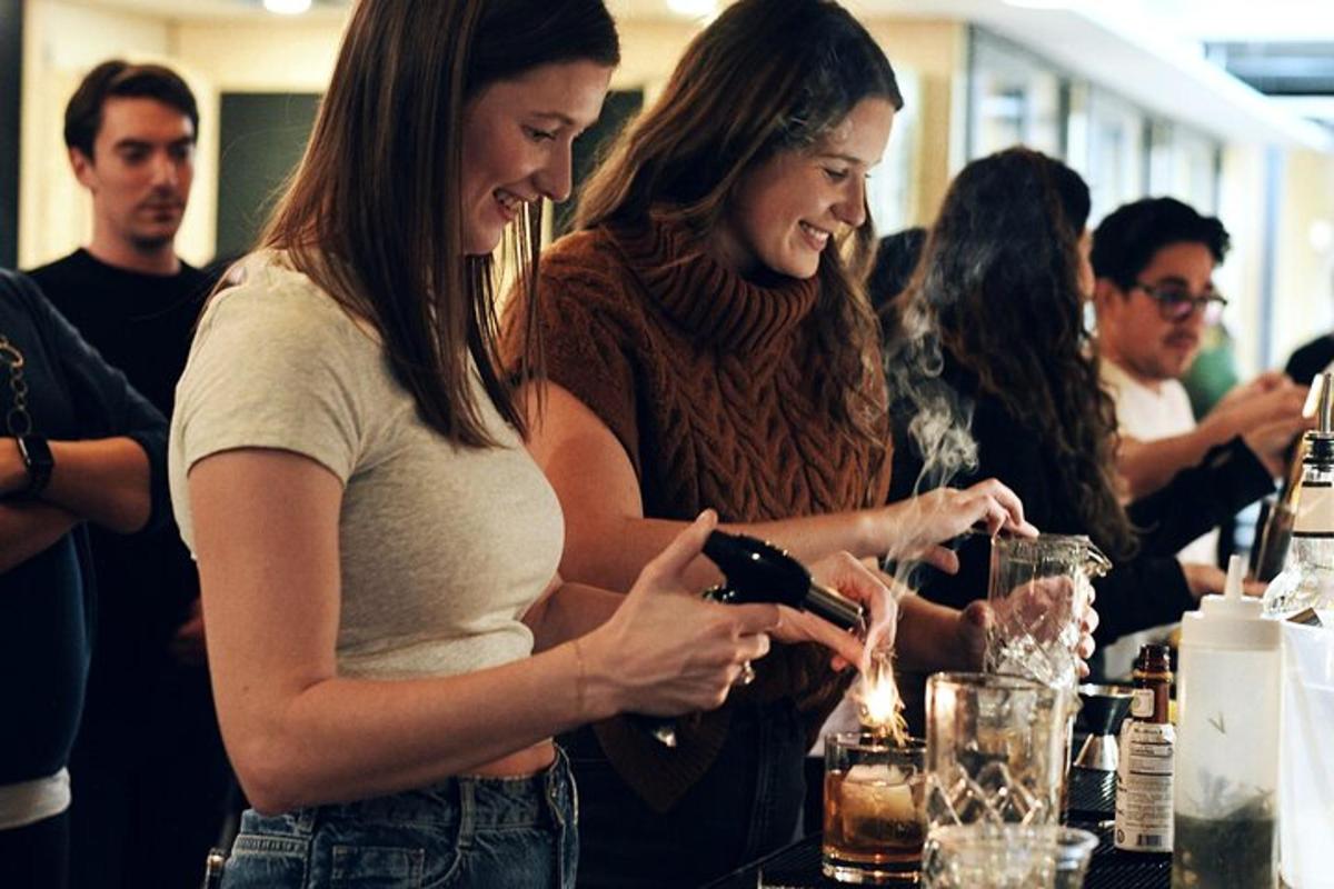 two women standing at a bar looking at a bottle of wine