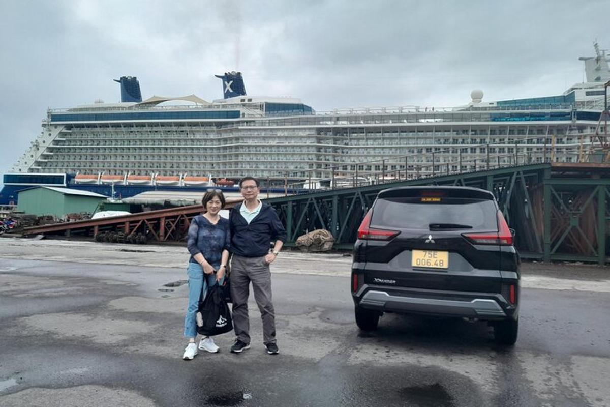 un uomo e una donna in piedi accanto a un'auto di fronte a una nave da crociera