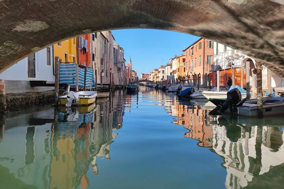 un uomo seduto su una barca in un canale sotto un ponte