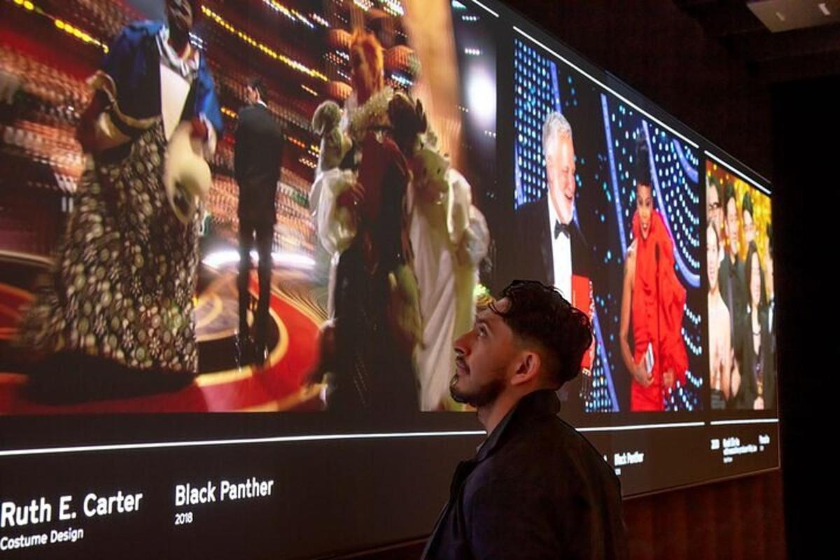 a man standing in front of a large screen with pictures of women
