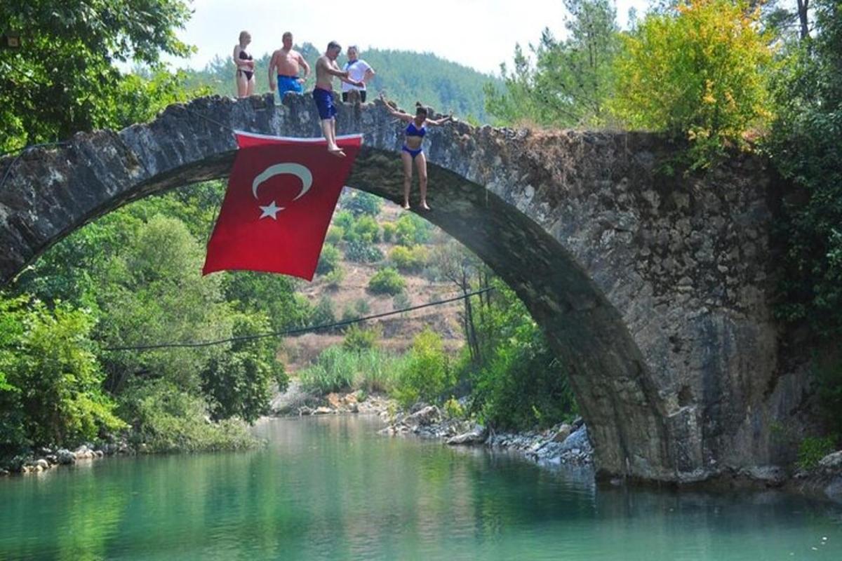 Personas de pie en un puente sobre un río con una bandera.