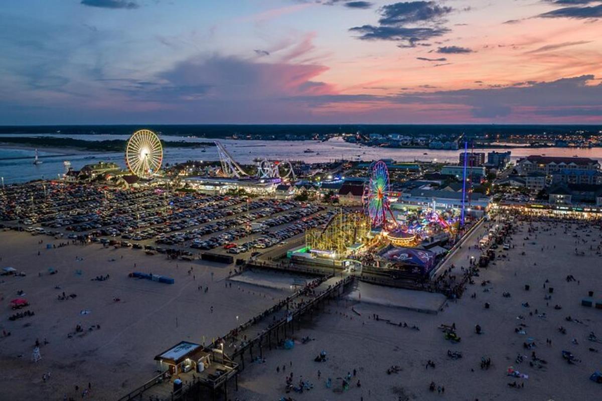 a crowded beach with a ferris wheel and a carnival
