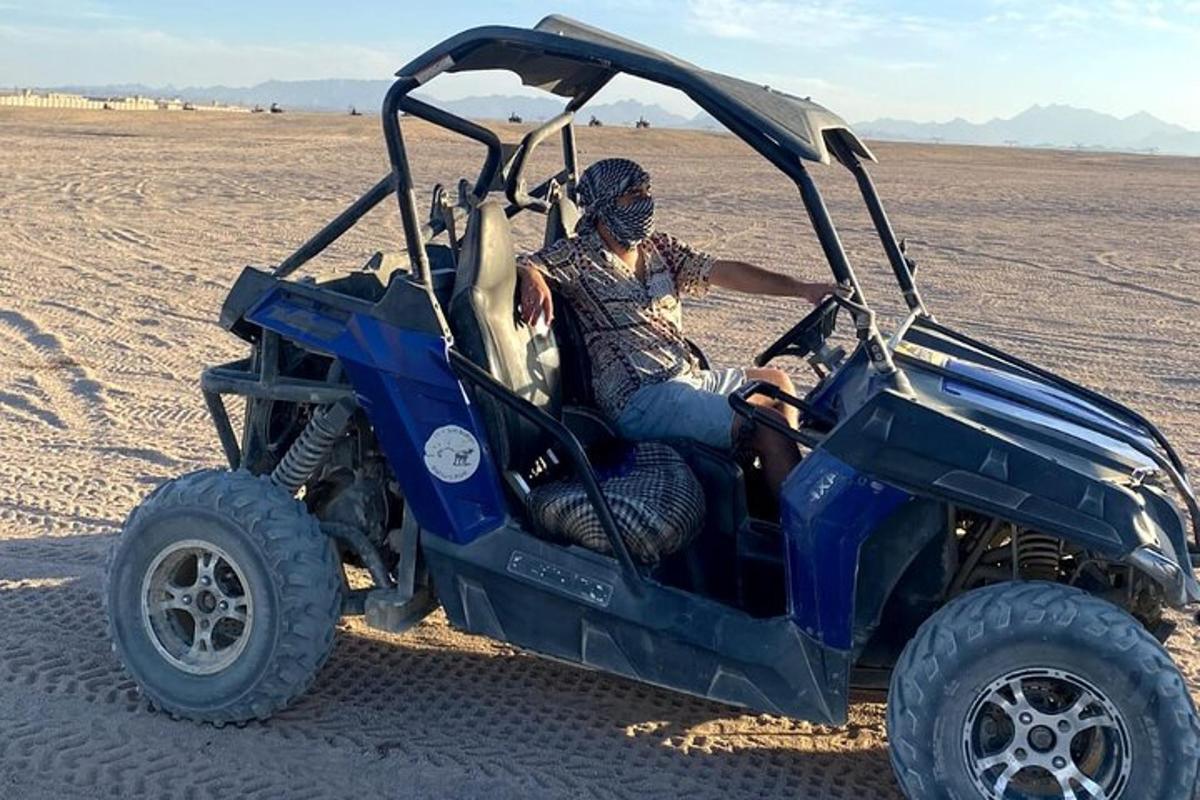 isang lalaking nakaupo sa isang asul na atv sa disyerto
