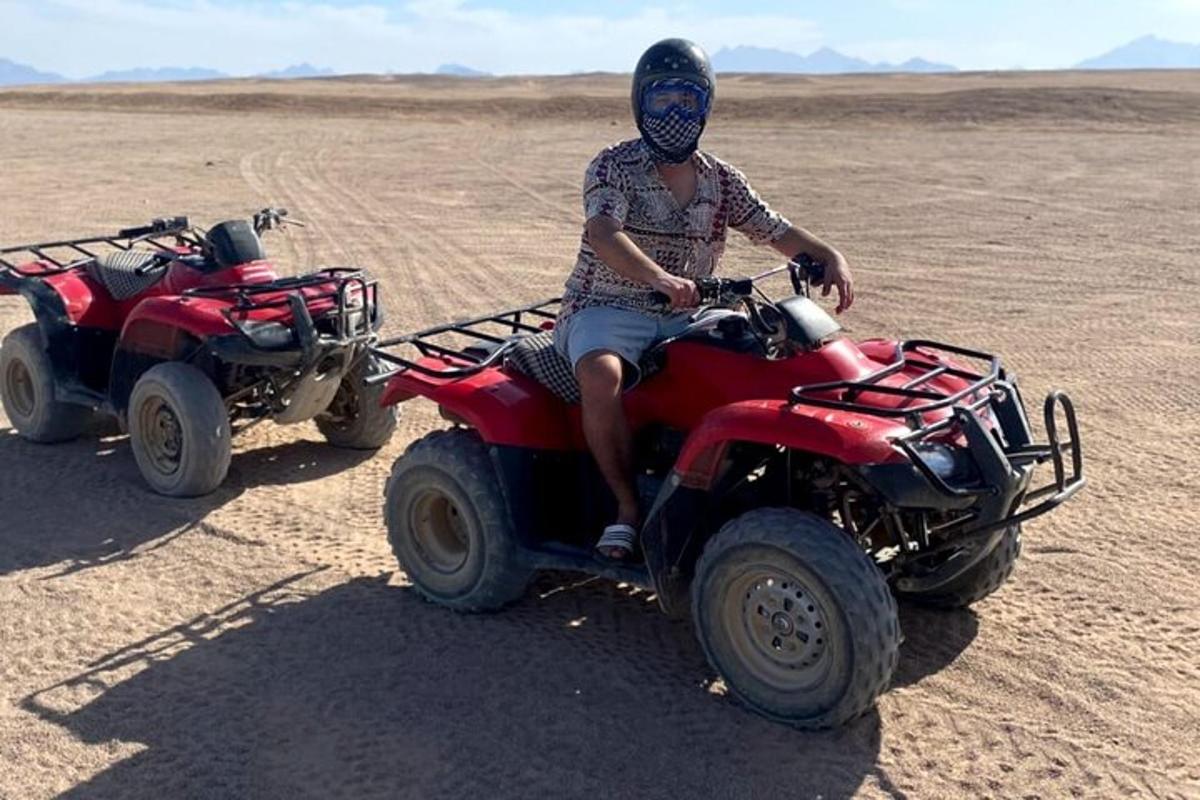isang lalaking nakaupo sa isang four wheeler sa disyerto