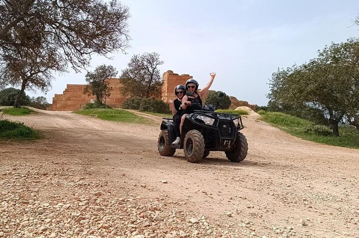 un homme et une femme sur un quad sur un chemin de terre