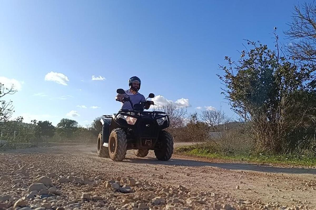 une personne conduisant un quad sur un chemin de terre
