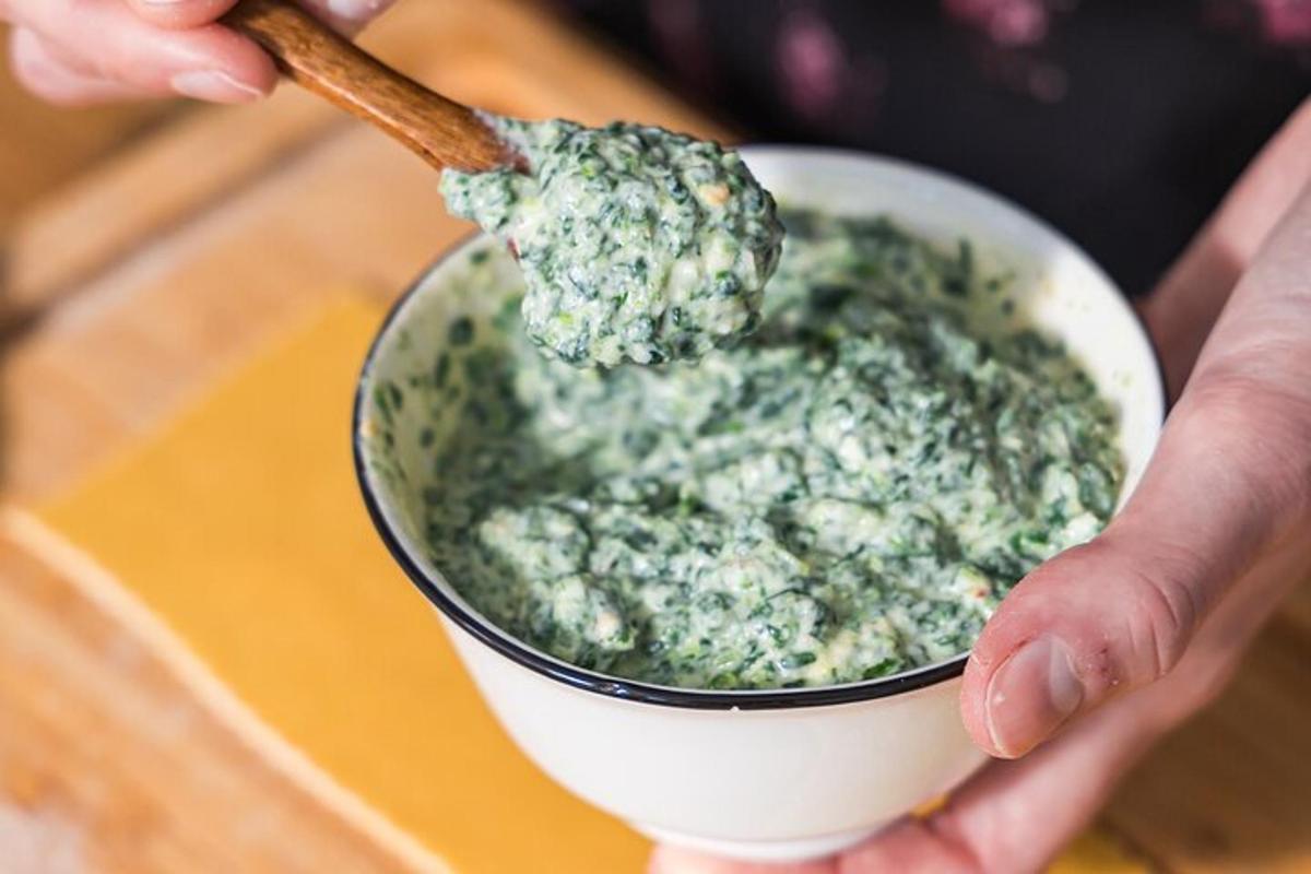 một người cầm một bát pesto bằng thìa gỗ