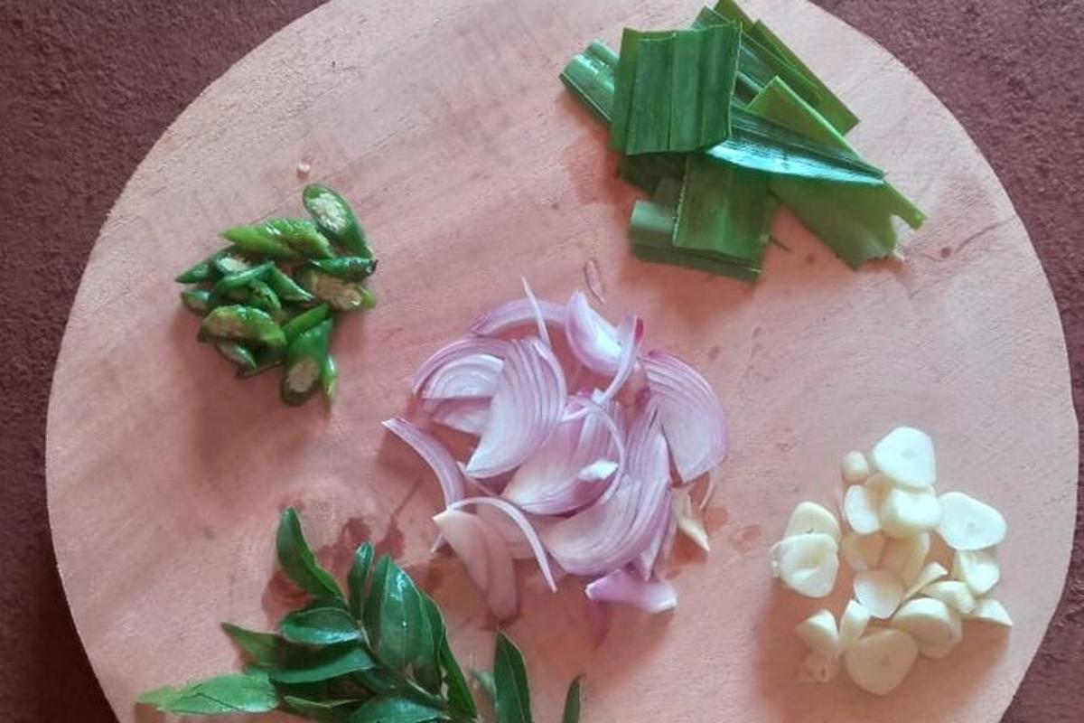 Una tabla de cortar con cebollas y otras verduras encima.