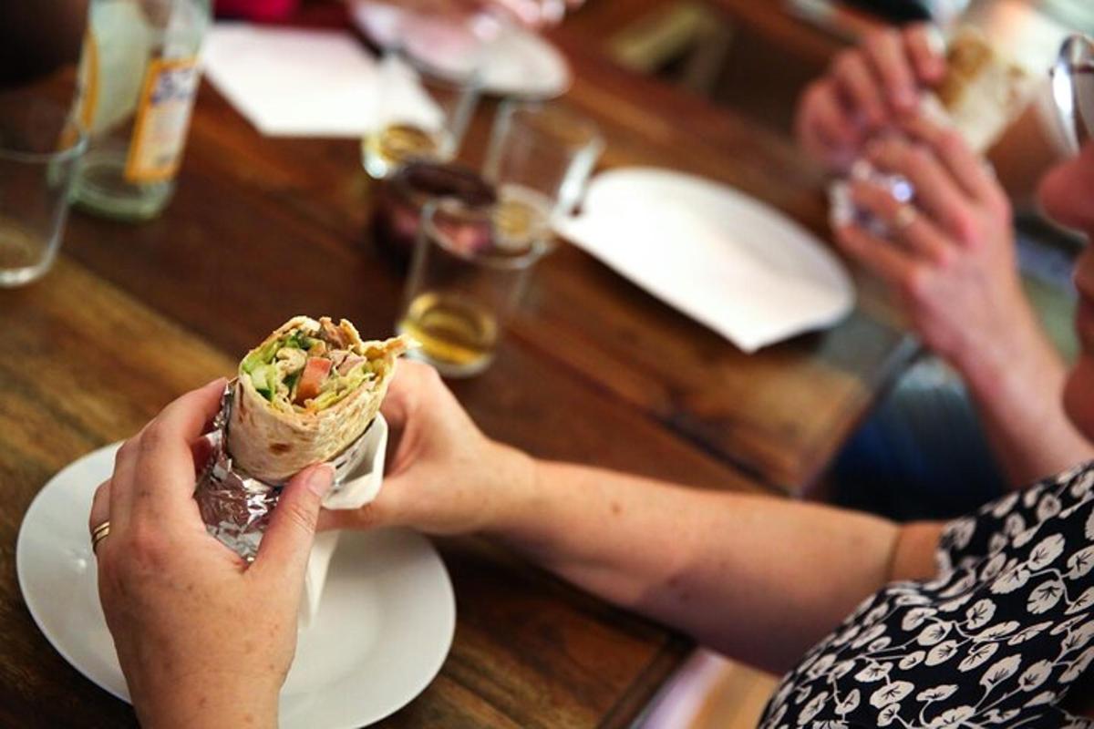 two people sitting at a table eating a sandwich
