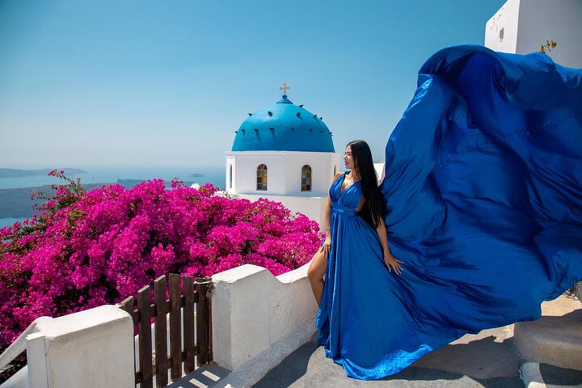 Una mujer con un vestido azul sentada en una pared junto a flores.