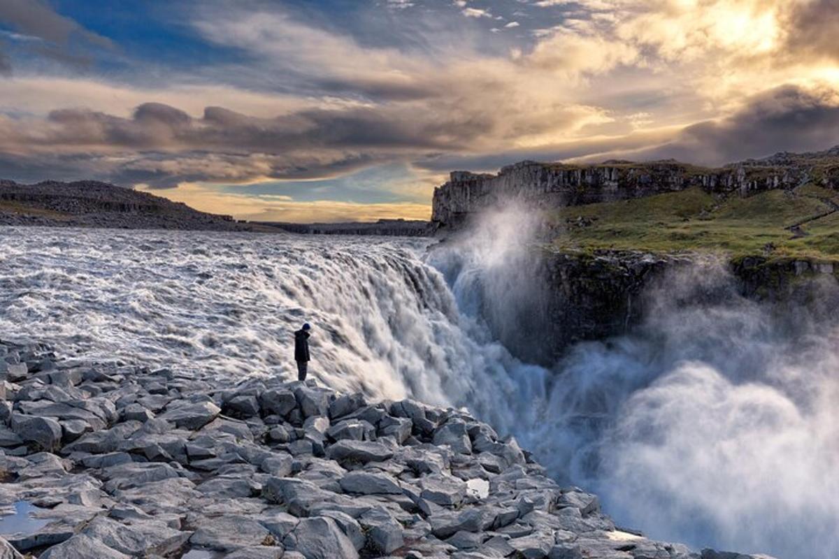 maður stendur á klettum nálægt fossi