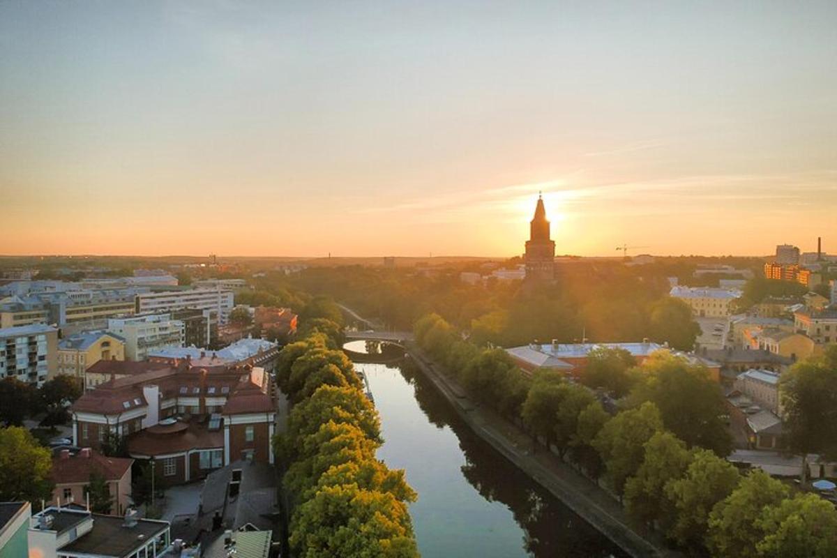 a city with a river and a clock tower at sunset
