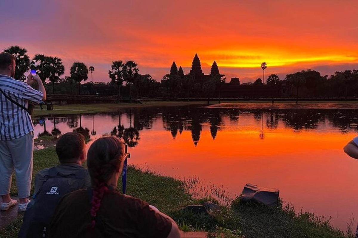 eine Gruppe von Menschen, die ein Foto von einem Sonnenuntergang machen