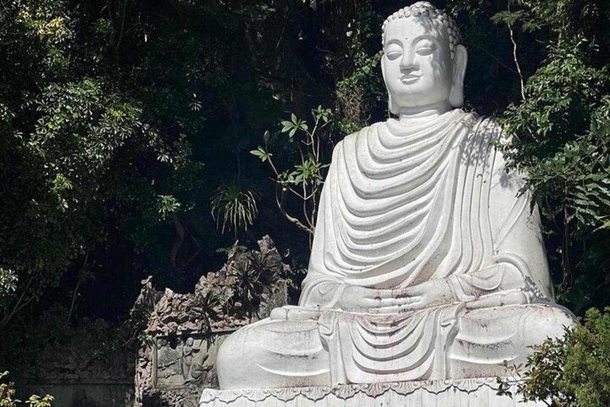 patung putih besar duduk di hadapan pokok