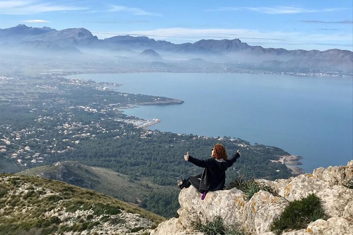 una donna seduta in cima a una montagna con le braccia tese