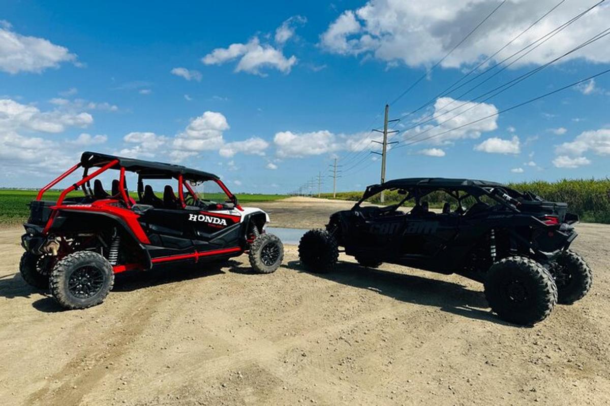 dvě čtyřkolky a auto zaparkované na prašné cestě