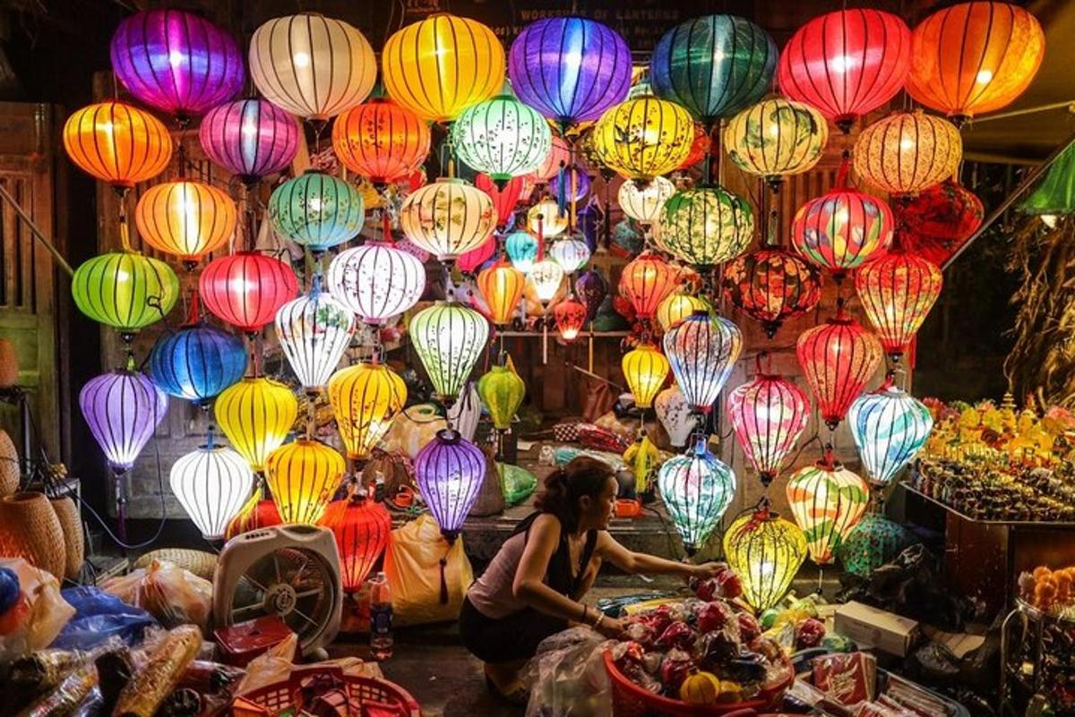 a woman sitting in front of a market with colorful lights