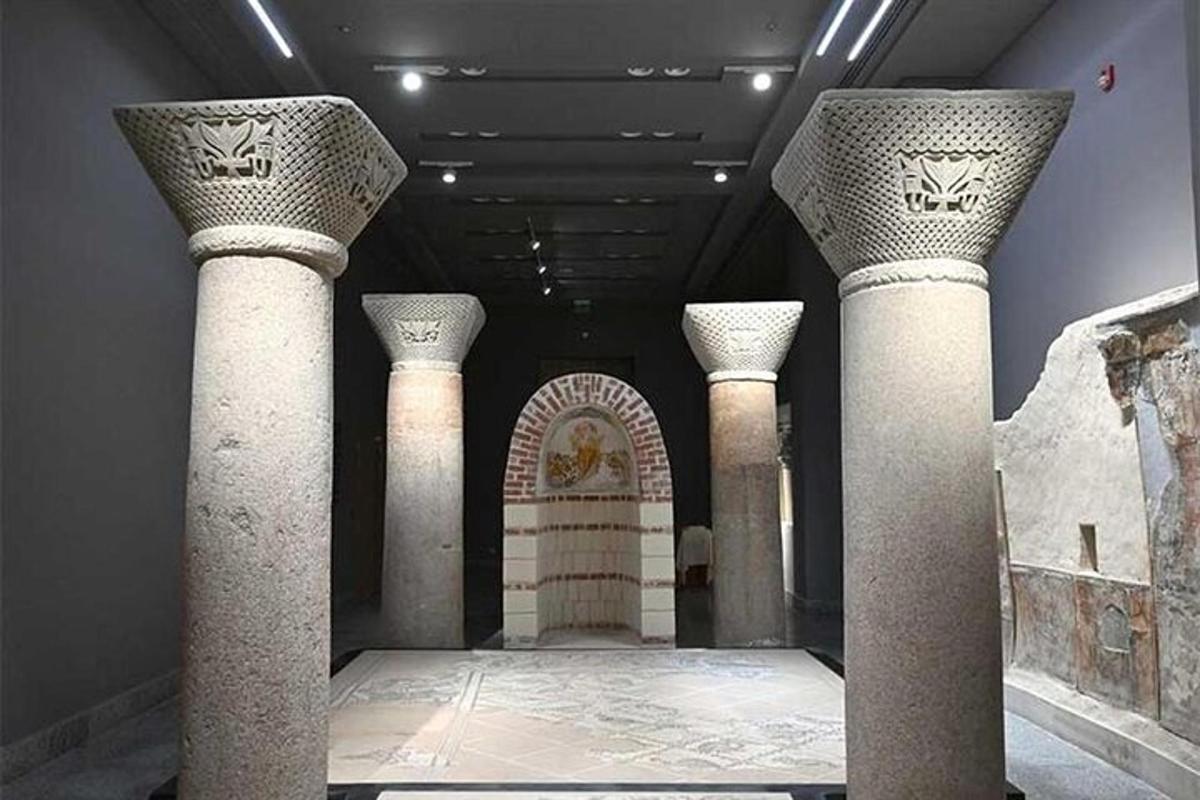 معرض متحفي يحتوي على أعمدة وغرفة تحتوي على قطع أثرية