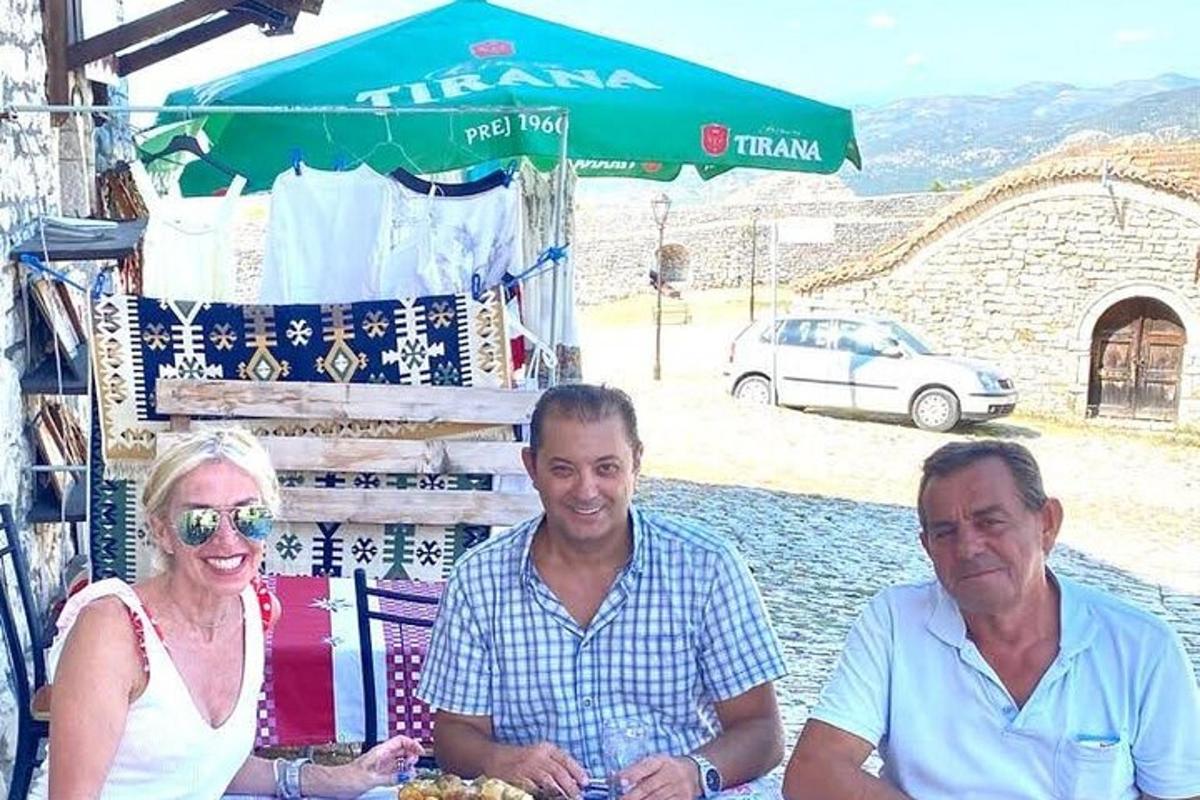 dvaja muži a žena sediaci pred trhoviskom