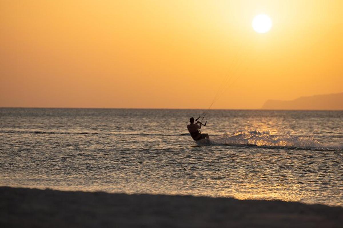 Un hombre practica kitesurf en el océano al atardecer
