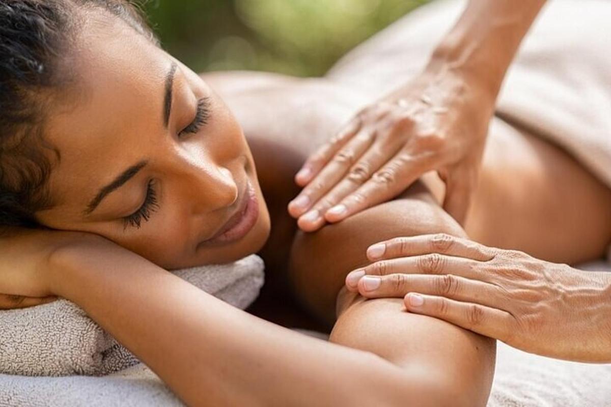 een vrouw die op een handdoek ligt en een massage krijgt