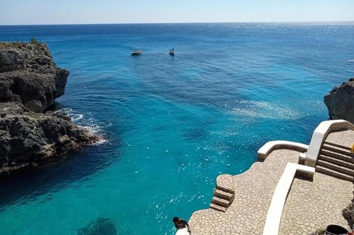 una dona asseguda en un banc mirant l'oceà