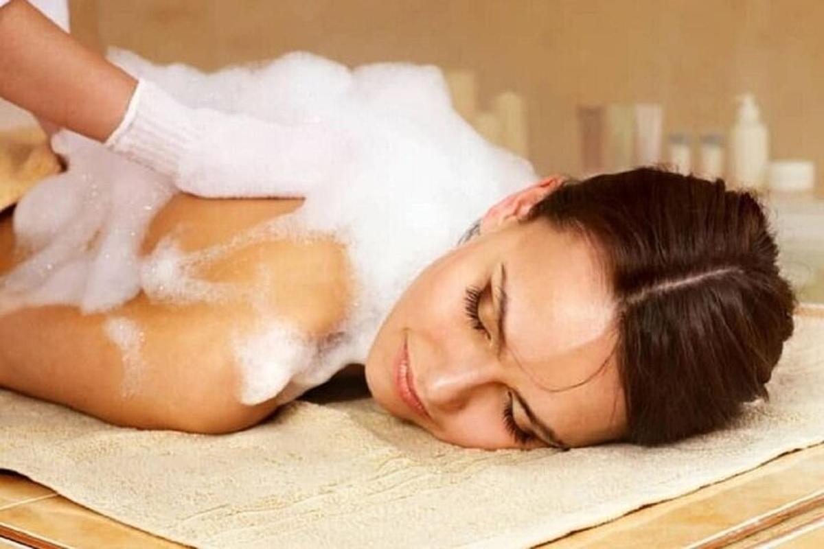 uma mulher deitada em uma toalha recebendo uma massagem