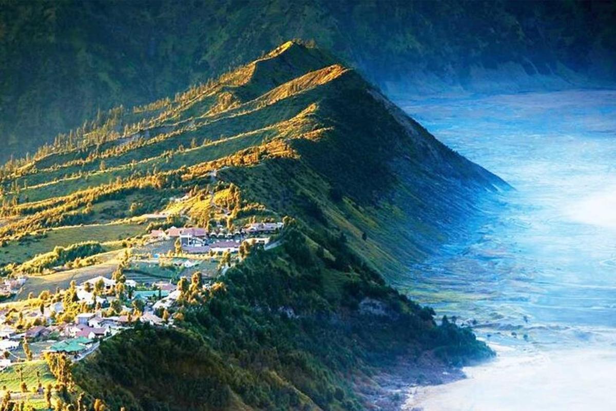 a mountain next to the ocean with houses on it
