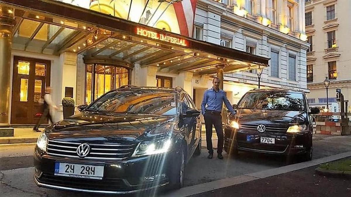 Ένας άντρας στέκεται δίπλα σε δύο αυτοκίνητα μπροστά σε ένα κτίριο
