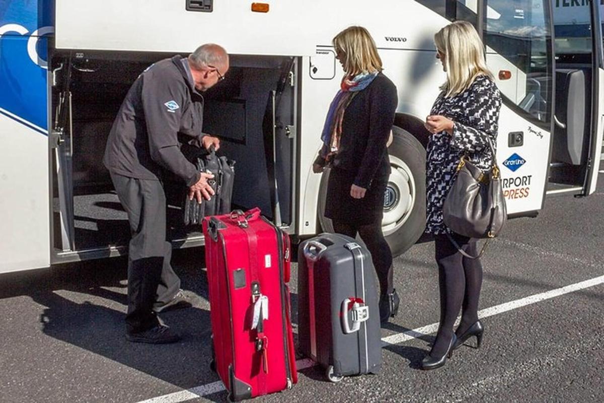 un uomo e due donne caricano i bagagli su un autobus