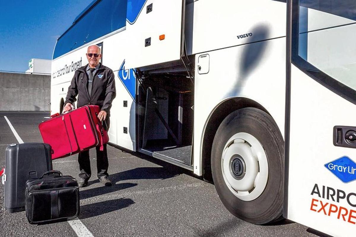 un uomo che tiene in mano una valigia rossa accanto a un autobus