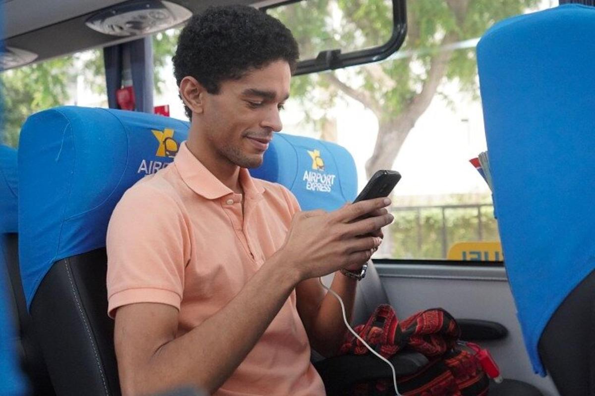 Un hombre sentado en un autobús mirando su teléfono celular.