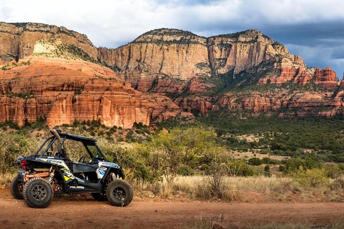 um quadriciclo estacionado em uma estrada de terra em frente a uma montanha