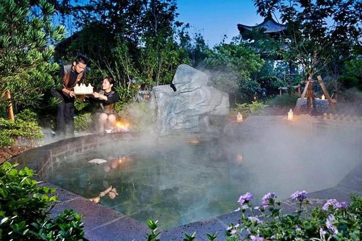 two people sitting in front of a fountain in a garden