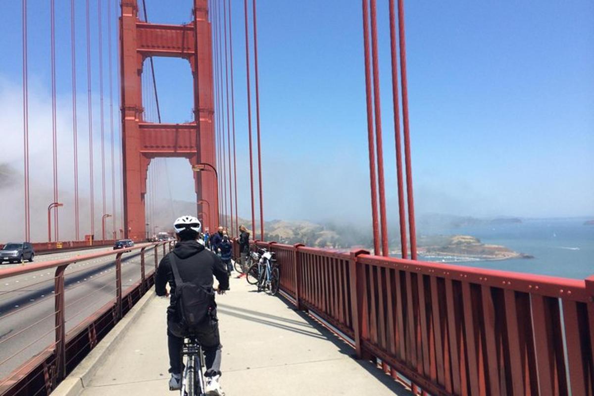muž jazdiaci na bicykli na moste Golden Gate