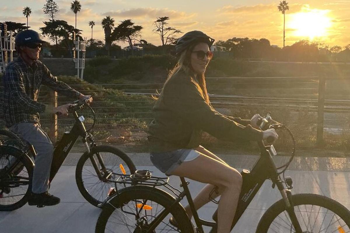 um homem e uma mulher andando de bicicleta ao pôr do sol