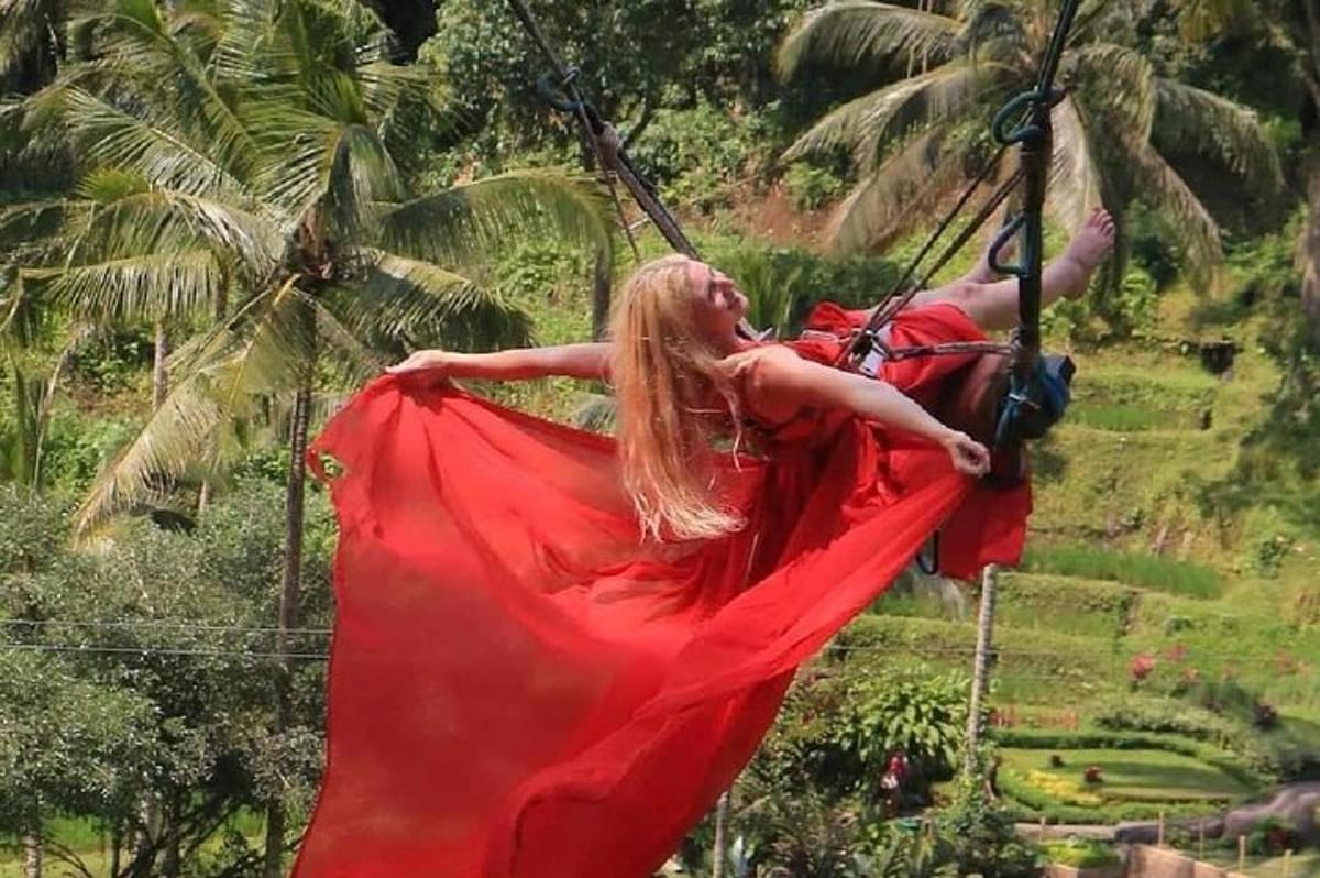 a man and a woman in a red dress on a swing